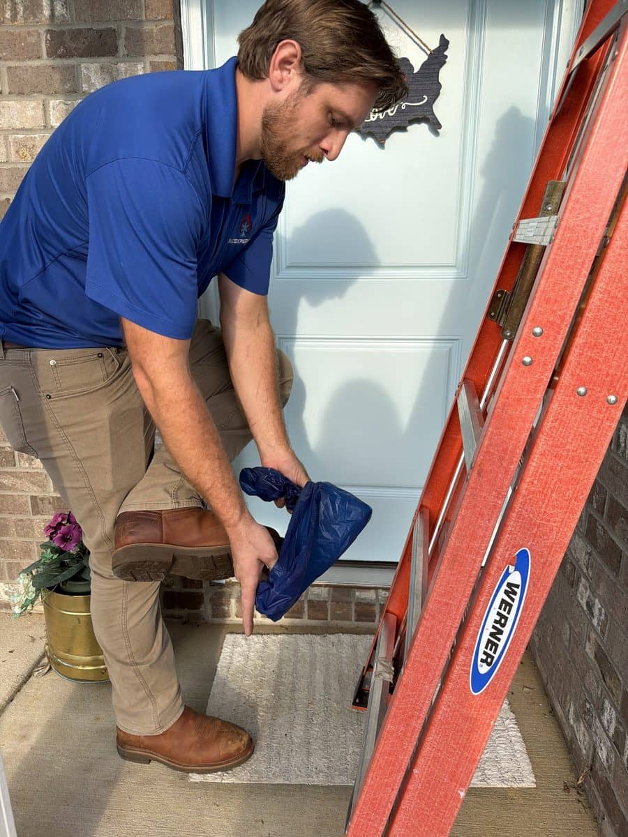 Landon Jahnke pulling on a shoe cover at a front door before stepping inside