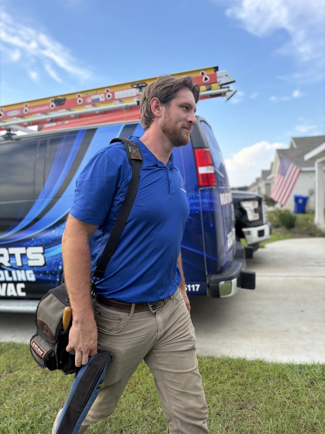 Landon Jahnke carrying tools from the ACExperts van up a residential driveway