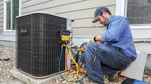 HVAC technician servicing a residential outdoor AC condenser with manifold gauges