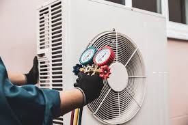 Technician checking refrigerant pressure gauges on an outdoor HVAC unit